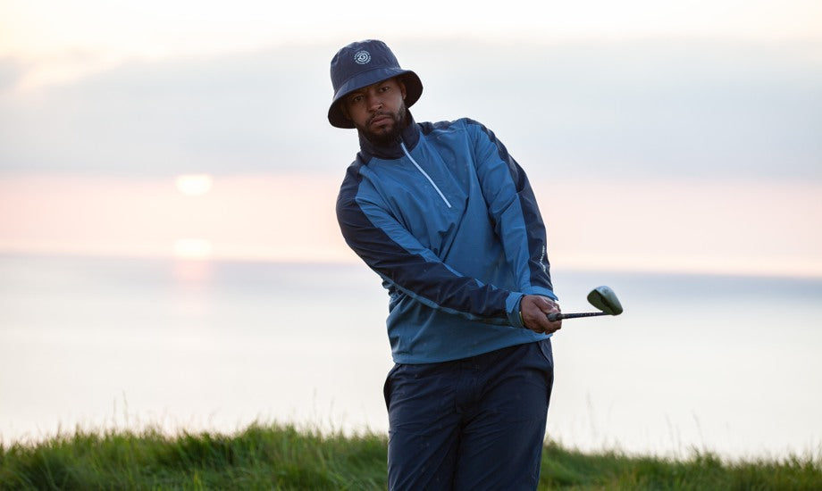 A male golfer holding his club wearing blue golf rain gear