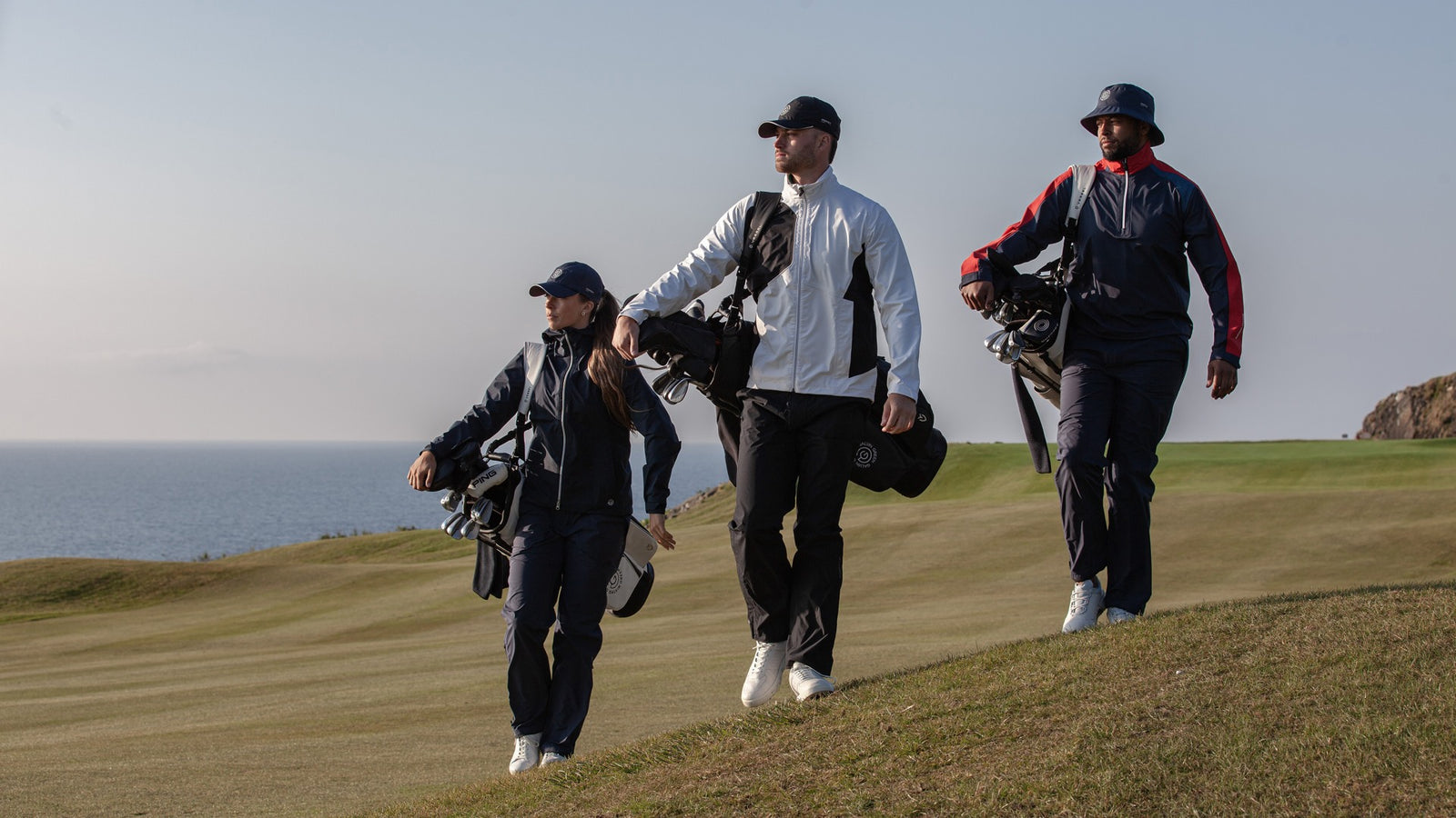 Three golfers, walking on a golfcourse wearing rain golf clothing