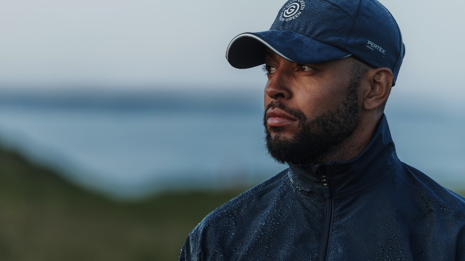 A male golfer wearing a navy golf rain hat.