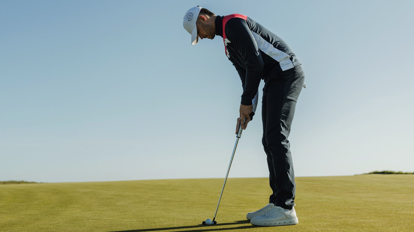 A male golfer holding his putter ready to hit the ball
