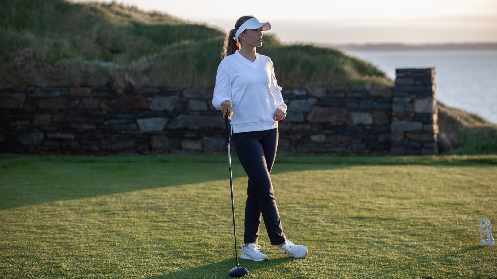 A female golfer standing with her club on a golf course