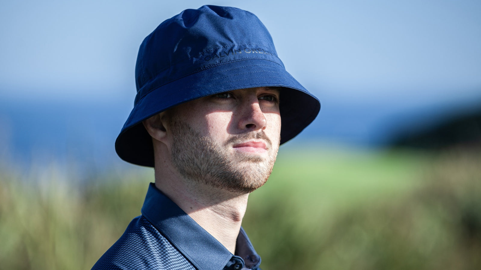 A male golfer wearing a navy bucket hat
